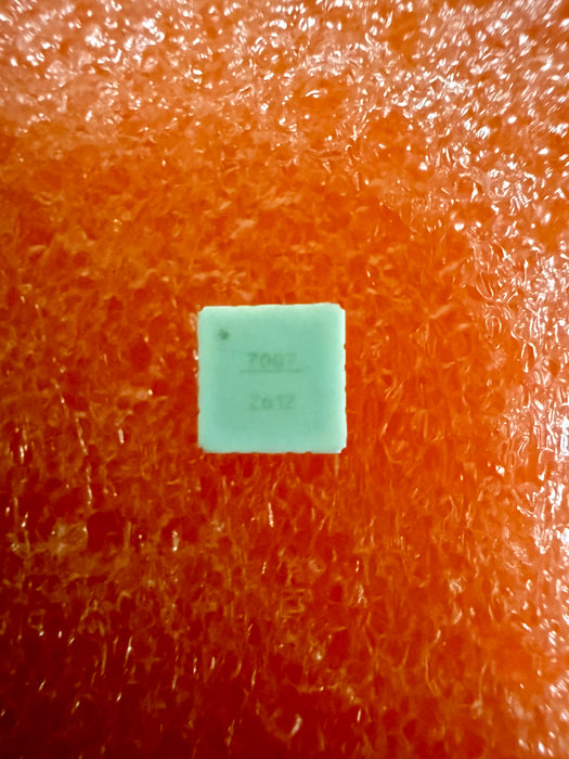 A small square mint-green plastic tag with stamped black numbers '7062' and '2012' on a highly textured, bright orange background.