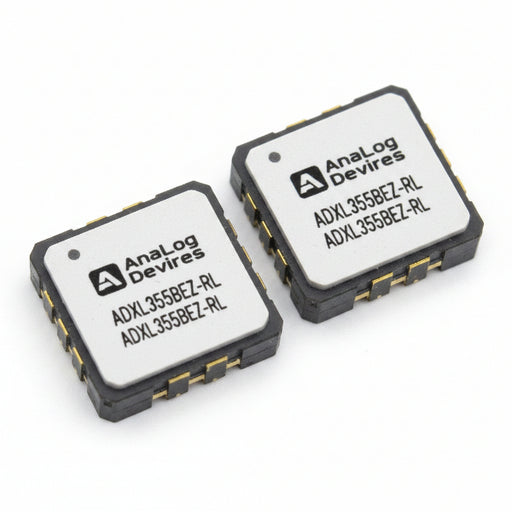 Two ADXL355BEZ-RL small electronic integrated circuit chips on a white background, one showing a white label with black text and the other showing the gold and gray solder pads of the chip.