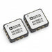 Two ADXL355BEZ-RL small electronic integrated circuit chips on a white background, one showing a white label with black text and the other showing the gold and gray solder pads of the chip.