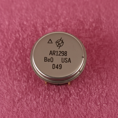 AR1298 - Metallic circular component with text and symbols on a pink textured background