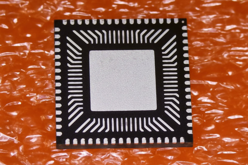 FT2232HQ electronic microchip with a black outer border, white pin points, and a silver center, placed on a textured orange surface.