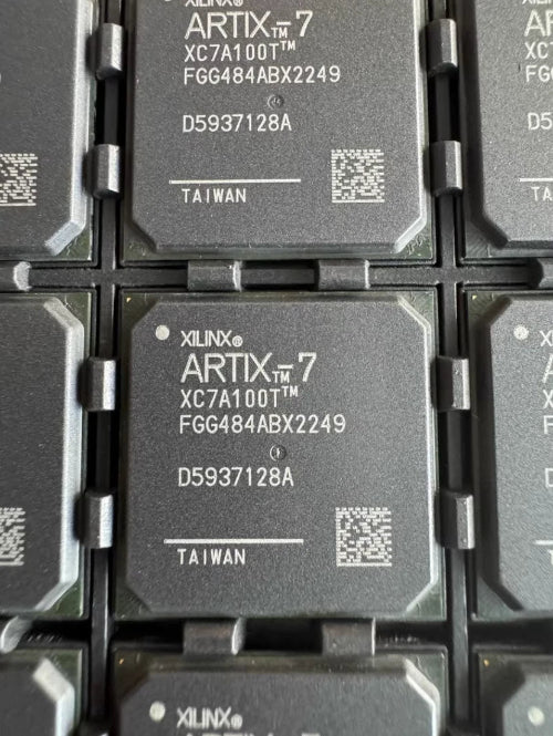 A close-up of multiple Xilinx Artix-7 FPGA chips arranged in a grid, showing the black integrated circuit packages with white printed text and QR codes.